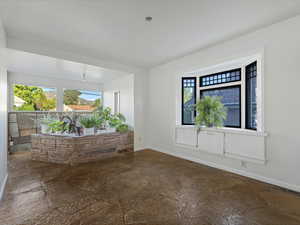 Spare room featuring stone tile floors, plenty of natural light, and baseboards
