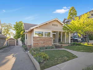 View of front of house with a garage, driveway, a front lawn, and an outdoor structure