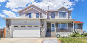 Traditional-style home featuring stone siding, a porch, concrete driveway, and an attached garage