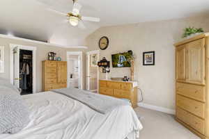 Bedroom with light carpet, lofted ceiling, baseboards, ceiling fan, and a spacious closet