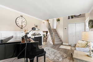 Living area with stairway, ornamental molding, wood finished floors, and baseboards
