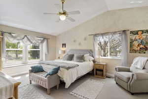 Bedroom featuring vaulted ceiling, multiple windows, light colored carpet, and baseboards