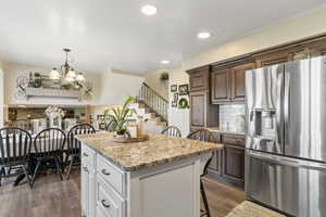 Kitchen with stainless steel fridge, a center island, dark wood-type flooring, a kitchen bar, and a chandelier