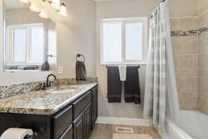 Bathroom with vanity, shower / bath combo with shower curtain, baseboards, and wood finished floors