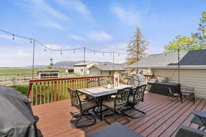 Wooden deck with outdoor dining space, a mountain view, fence, and a grill