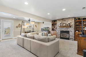 Living area with carpet floors, recessed lighting, and a stone fireplace