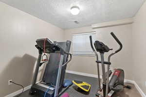 Exercise room with baseboards and a textured ceiling