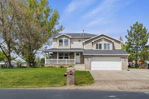 View of front of home featuring covered porch, an attached garage, concrete driveway, a front yard, and brick siding