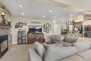 Living area featuring a stone fireplace, recessed lighting, carpet, and baseboards
