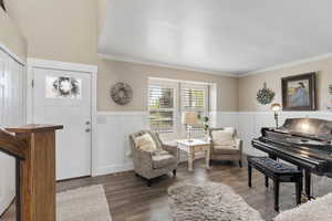 Foyer with crown molding, a wainscoted wall, wood finished floors, a decorative wall, and a textured ceiling