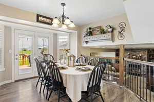 Dining space with wood finished floors, a chandelier, and baseboards