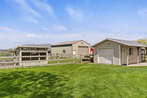 View of yard with a detached garage, an outbuilding, and fence