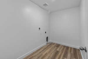 Clothes washing area featuring hookup for an electric dryer, hookup for a washing machine, wood finished floors, and baseboards