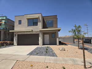 View of front facade with stucco siding, driveway, an attached garage, and stone siding