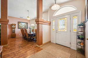 Entrance foyer featuring a ceiling fan, baseboards, healthy amount of natural light, a textured ceiling, and light tile patterned flooring
