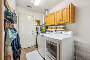 Washroom featuring independent washer and dryer, water heater, and cabinet space