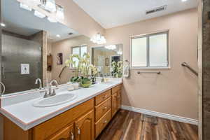 Bathroom with baseboards, wood finished floors, a stall shower, and double vanity