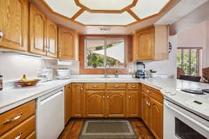 Kitchen with white appliances, a sink, light countertops, and dark wood-type flooring