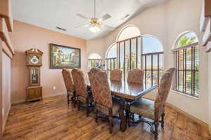 Dining room featuring wood finished floors, a textured ceiling, ceiling fan, baseboards, and lofted ceiling