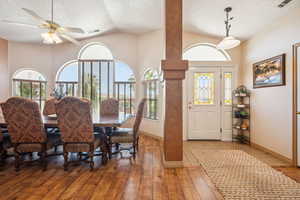 Dining area featuring a textured ceiling, lofted ceiling, hardwood / wood-style floors, ceiling fan, and ornate columns