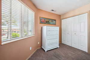 Bedroom featuring carpet flooring, a closet, baseboards, and a textured ceiling