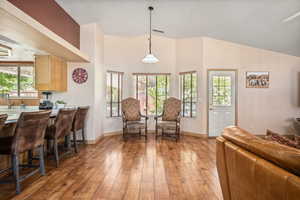 Dining space with light wood finished floors, baseboards, and vaulted ceiling