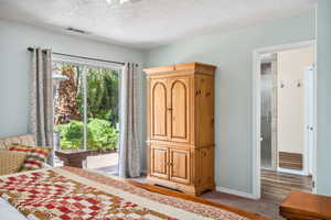 Bedroom featuring a textured ceiling, baseboards, light colored carpet, and access to outside