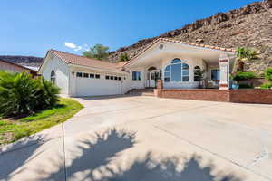 Mediterranean / spanish-style house with concrete driveway, a tiled roof, a mountain view, stucco siding, and an attached garage