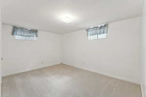 Below grade area featuring light colored carpet and baseboards