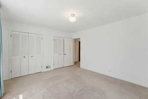 Unfurnished bedroom with multiple closets, carpet flooring, and baseboards