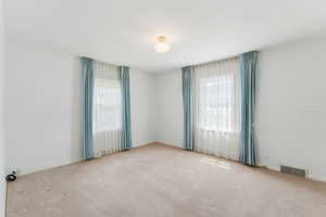 Empty room with healthy amount of natural light, carpet floors, and baseboards