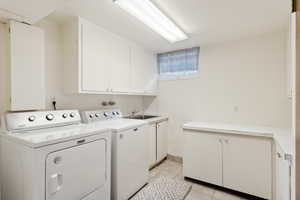 Laundry room with cabinet space, independent washer and dryer, and light tile patterned flooring