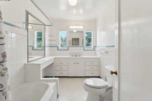 Bathroom featuring tile patterned flooring, a tub, toilet, plenty of natural light, and tile walls