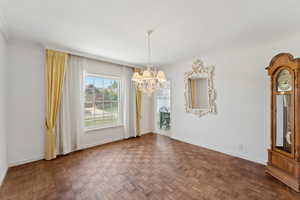 Unfurnished dining area featuring a chandelier, baseboards, and crown molding