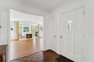 Foyer featuring ornamental molding and a warm lit fireplace