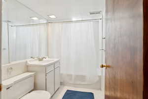 Full bath with tile patterned floors, toilet, shower / tub combo, and vanity