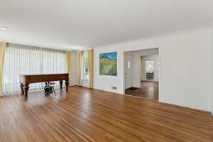 Living room with wood finished floors, ornamental molding, and baseboards