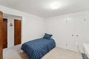 Bedroom with light colored carpet and a closet