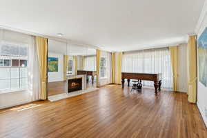 Living area featuring wood finished floors, a warm lit fireplace, crown molding, and baseboards