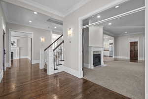 Unfurnished living room featuring a tiled fireplace, hardwood / wood-style flooring, recessed lighting, stairway, and baseboards