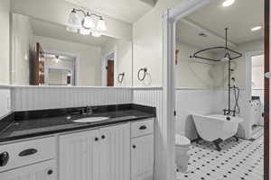 Bathroom with a wainscoted wall, a freestanding tub, vanity, and toilet