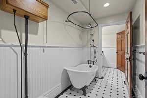 Full bath with wainscoting and a freestanding tub