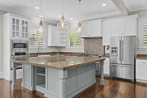 Kitchen with appliances with stainless steel finishes, open shelves, a sink, dark wood-style floors, and crown molding