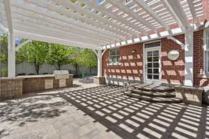 View of patio with a fenced backyard, area for grilling, a pergola, and an outdoor kitchen