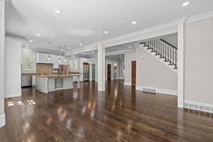 Unfurnished living room featuring dark wood-type flooring, recessed lighting, a sink, crown molding, and baseboards