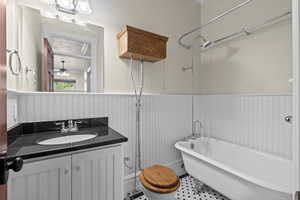 Bathroom with a wainscoted wall, a soaking tub, vanity, and ceiling fan