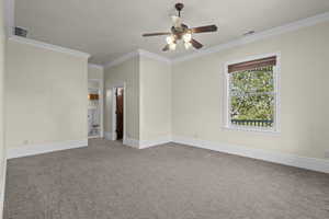 Carpeted spare room featuring a ceiling fan, crown molding, and baseboards