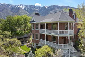 View of front of property with a chimney, a balcony, brick siding, a mountain view, and a porch