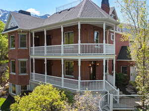 View of front facade featuring a balcony, brick siding, a shingled roof, and a porch