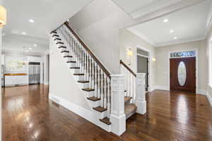Entrance foyer featuring stairs, dark wood-type flooring, recessed lighting, baseboards, and ornamental molding